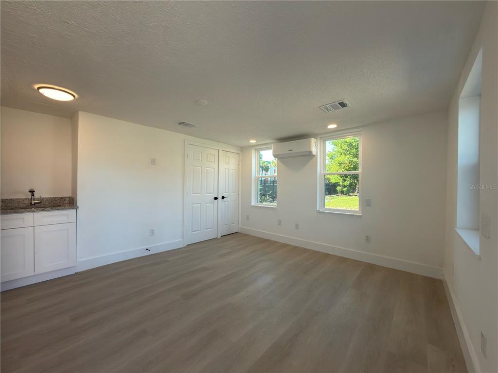 A bright room features light wood-look flooring, white walls, a small kitchenette, and windows — 401 E COLUMBUS DRIVE UNIT 2, TAMPA, FL