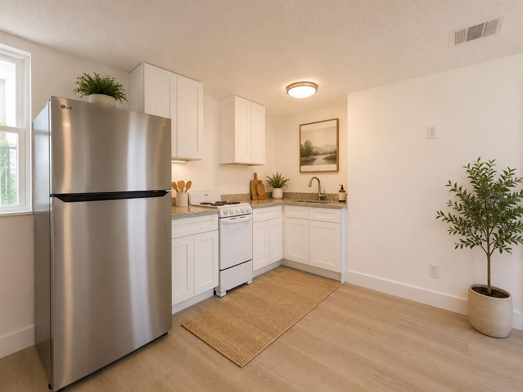 A kitchen with white cabinets, stainless steel appliances, light wood flooring, and a potted plant — 401 E COLUMBUS DRIVE UNIT 2, TAMPA, FL