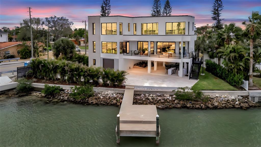 A modern entryway features light wood floors, a round black table, and a glass elevator — 7176 S SHORE DRIVE S, ST PETERSBURG, FL