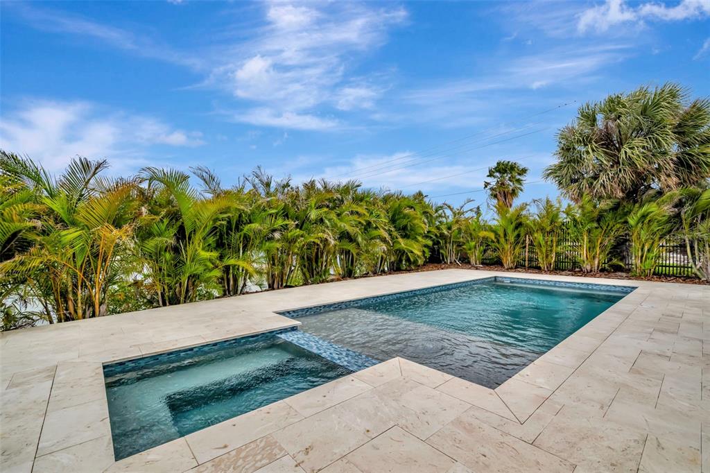 A bright, open-concept living room features a white sectional sofa, armchairs, and a modern kitchen — 7176 S SHORE DRIVE S, ST PETERSBURG, FL