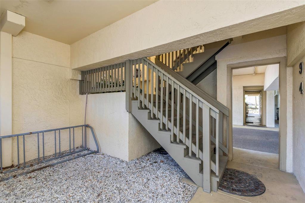 An outdoor staircase with gray railings leads to an upper level near a bike rack — 20204 GULF BOULEVARD UNIT 9, INDIAN SHORES, FL