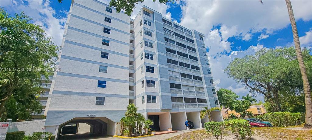 A multi-story residential apartment building with a ground-level parking entrance and surrounding palm trees — 3301 Spanish Moss Terrace # 219, Lauderhill FL 33319, LAUDERHILL, FL