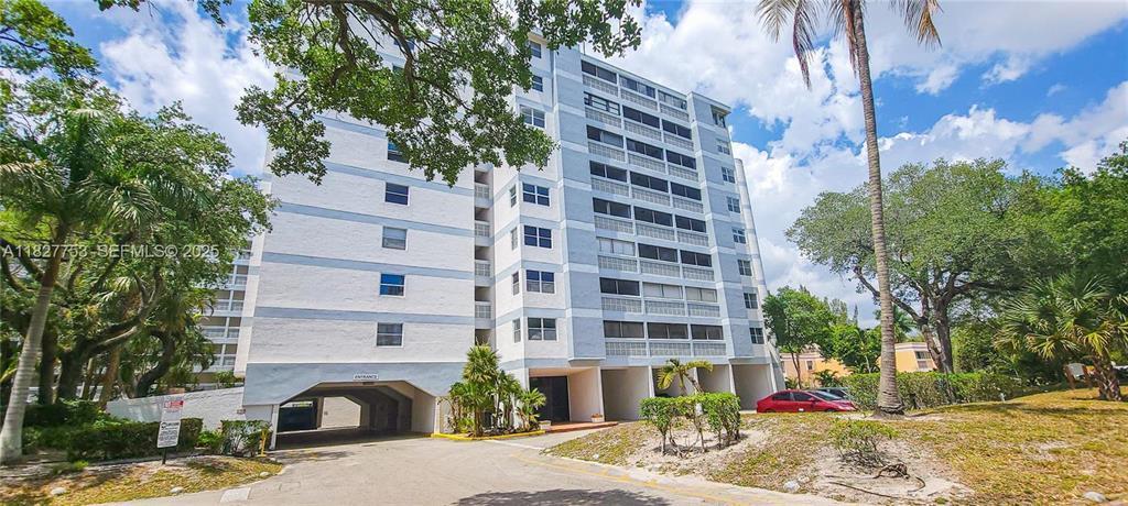 A multi-story residential apartment building with a covered ground-level entrance and surrounding trees — 3301 Spanish Moss Terrace # 219, Lauderhill FL 33319, LAUDERHILL, FL