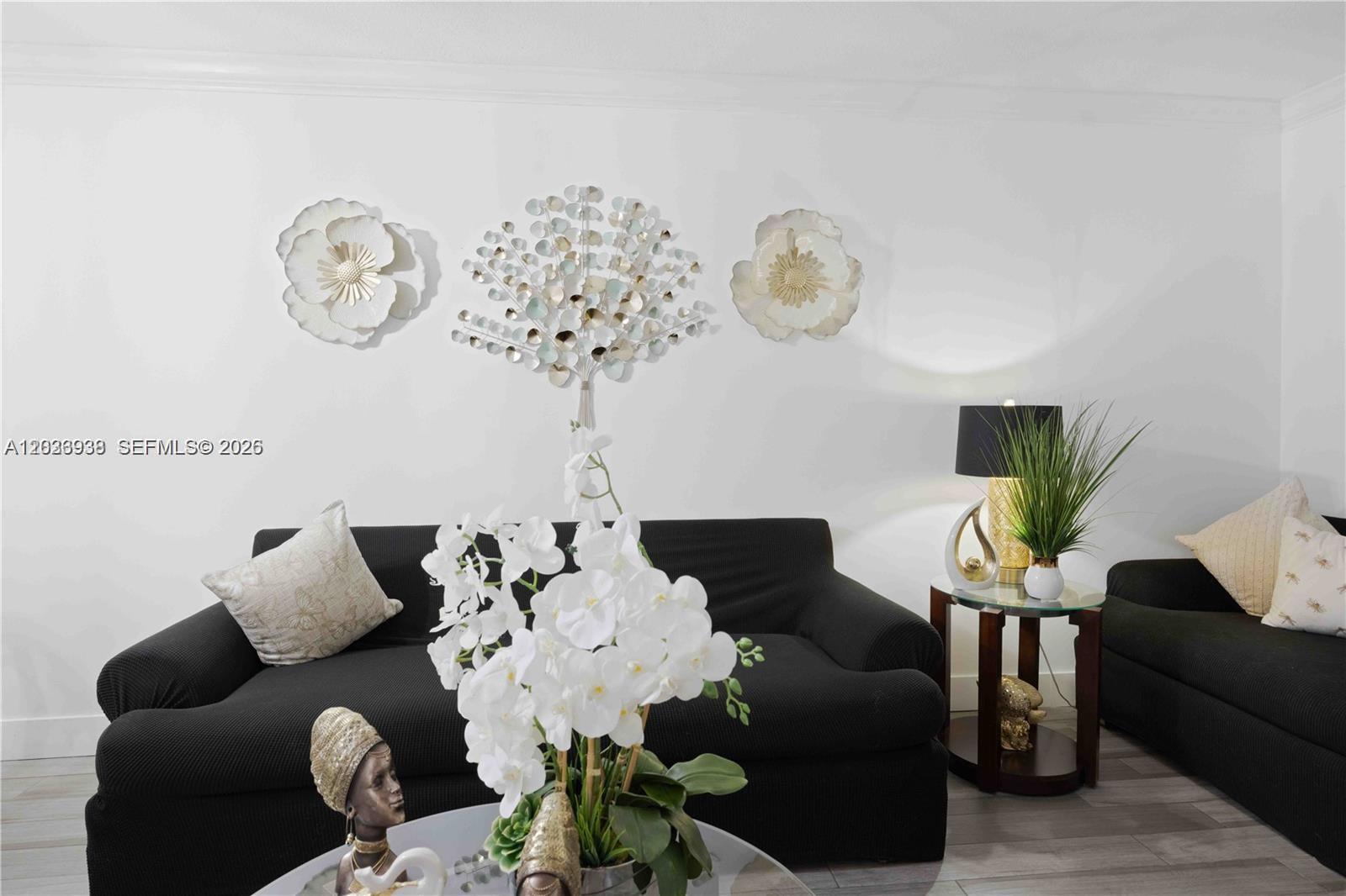 A living room features two black sofas, a glass-topped side table, and wall-mounted floral decor — 12505 NW 11th Ln # 109, Miami FL 33182, MIAMI, FL