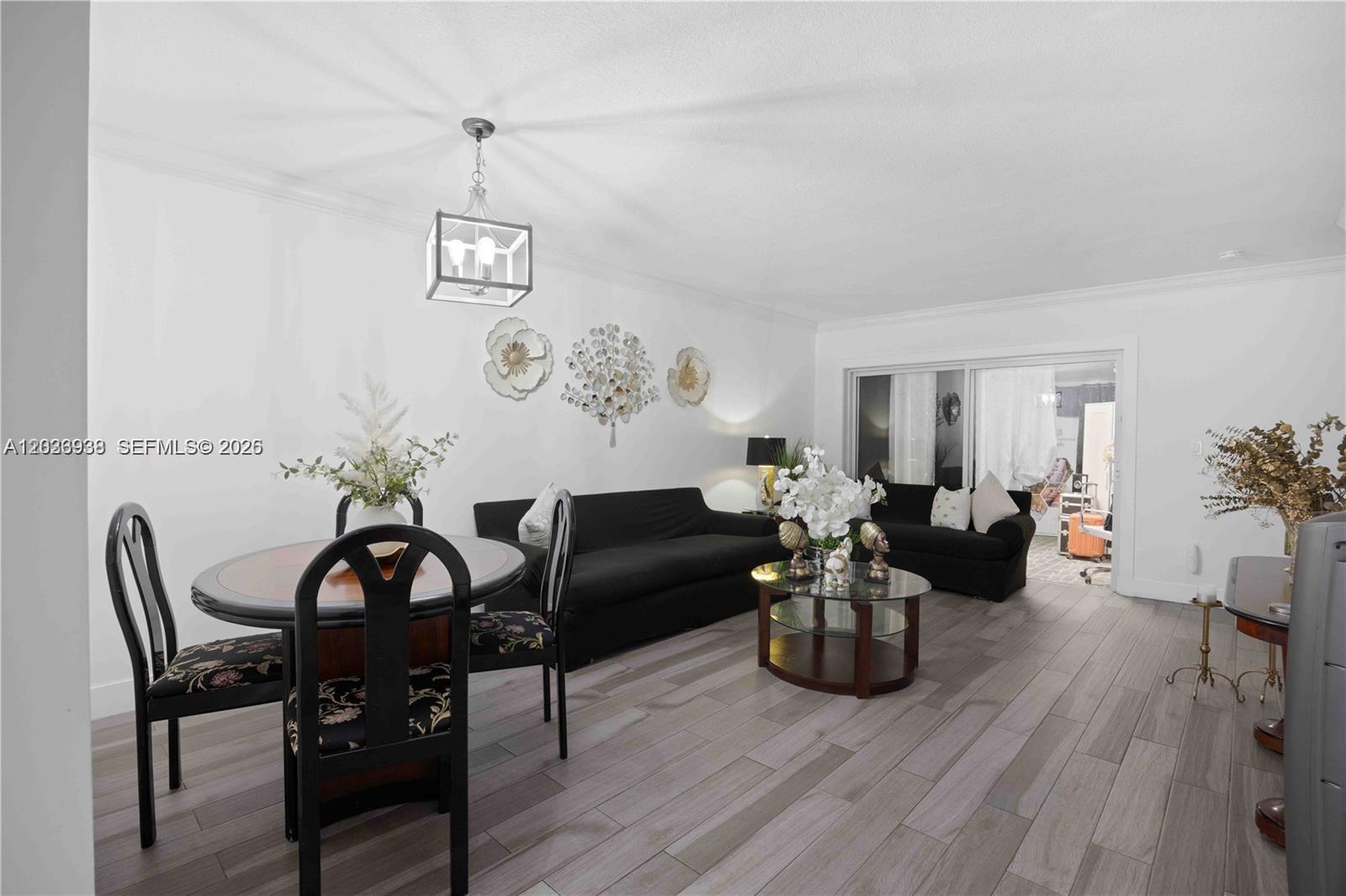 A living and dining area features black sofas, a round table, and light wood flooring — 12505 NW 11th Ln # 109, Miami FL 33182, MIAMI, FL