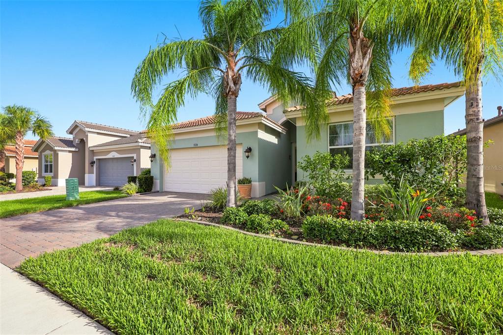 A light green single-story house with a two-car garage and palm trees in the front — 5124 HIGHLAND POINTE COURT, WIMAUMA, FL