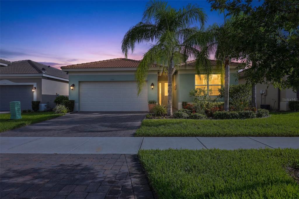 A single-story house with a green stucco exterior, a two-car garage, and palm trees — 5124 HIGHLAND POINTE COURT, WIMAUMA, FL