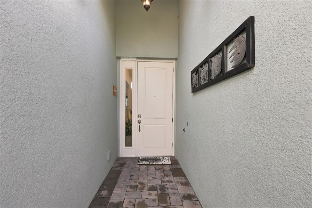 A white front door with a side window sits at the end of a paved entryway — 5124 HIGHLAND POINTE COURT, WIMAUMA, FL
