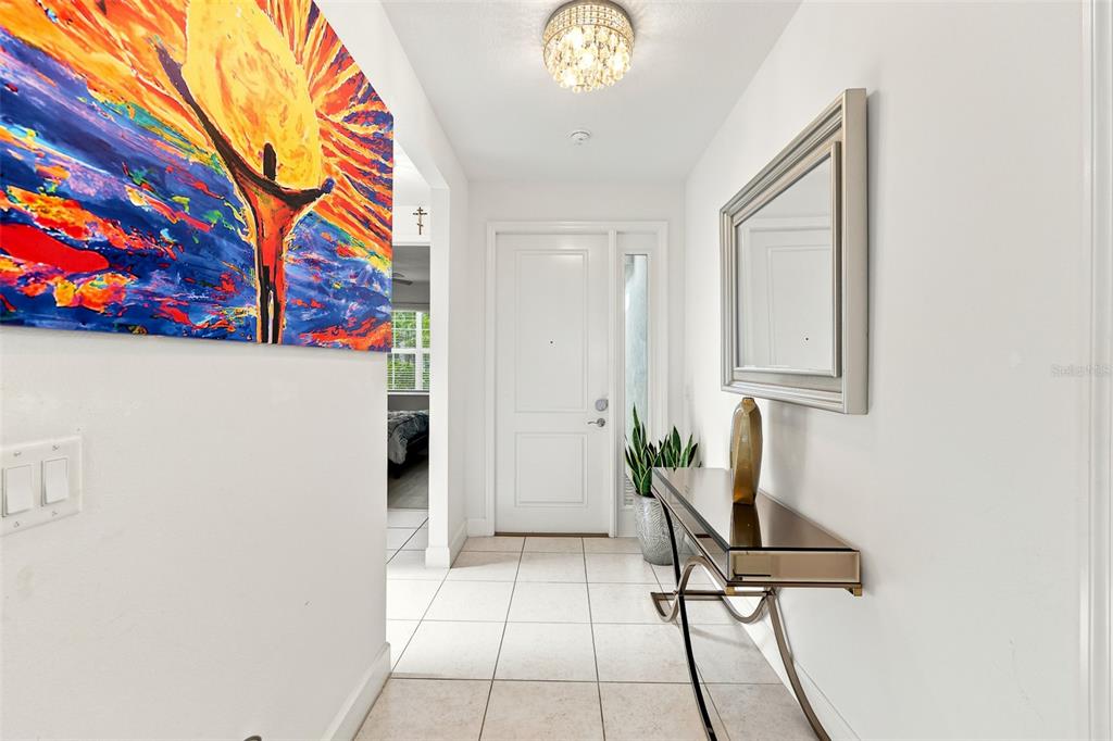 A bright entryway features white walls, tile flooring, a console table, and a large painting — 5124 HIGHLAND POINTE COURT, WIMAUMA, FL