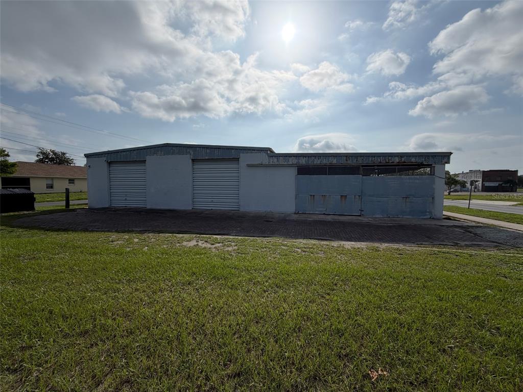 A single-story commercial building with two roll-up garage doors and an attached open-air storage area — 111 W PARKER STREET, LAKELAND, FL