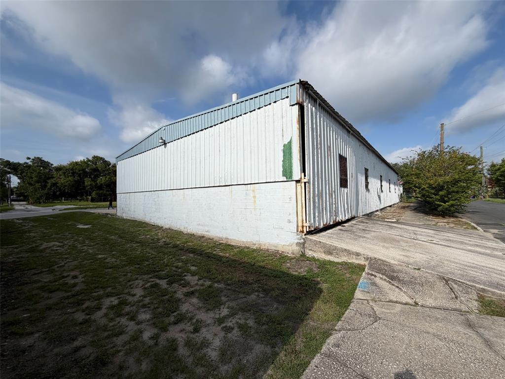 A white metal and concrete block warehouse building stands on a grassy lot — 111 W PARKER STREET, LAKELAND, FL