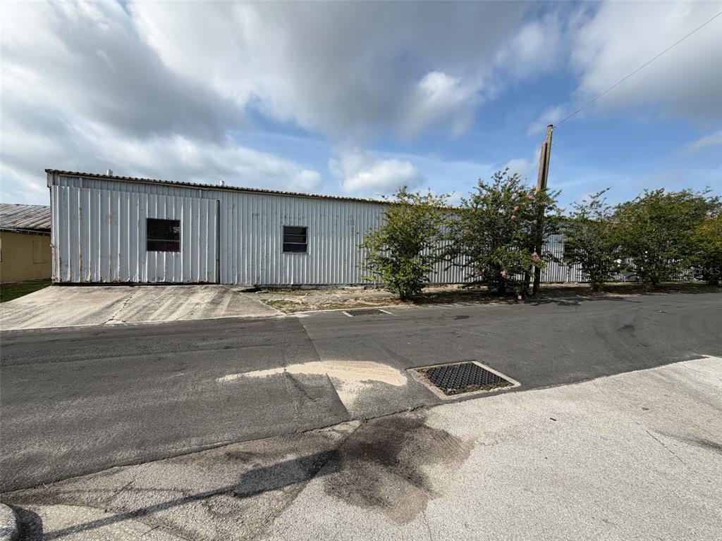 A long, single-story industrial building with white metal siding stands beside a paved street — 111 W PARKER STREET, LAKELAND, FL