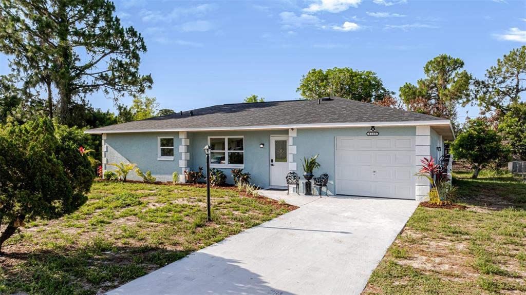 A light blue single-story house with a white garage door and a concrete driveway — 4211 5TH STREET W, LEHIGH ACRES, FL