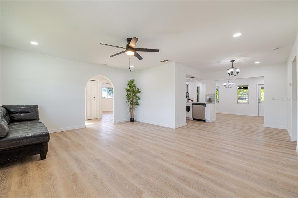 An open-concept living and dining area features light wood-look flooring and a ceiling fan — 4211 5TH STREET W, LEHIGH ACRES, FL
