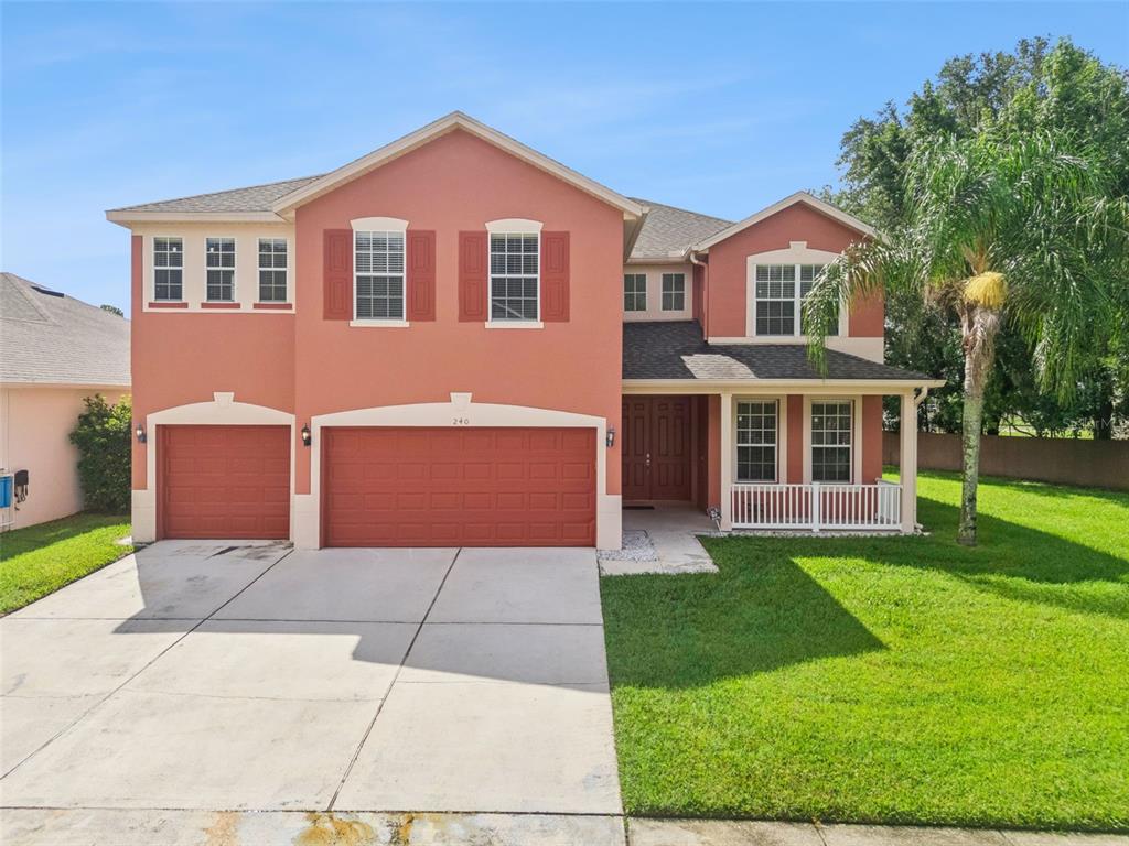 A two-story house with a terracotta exterior, a three-car garage, and a front porch — 240 MAGNOLIA PARK TRAIL, SANFORD, FL