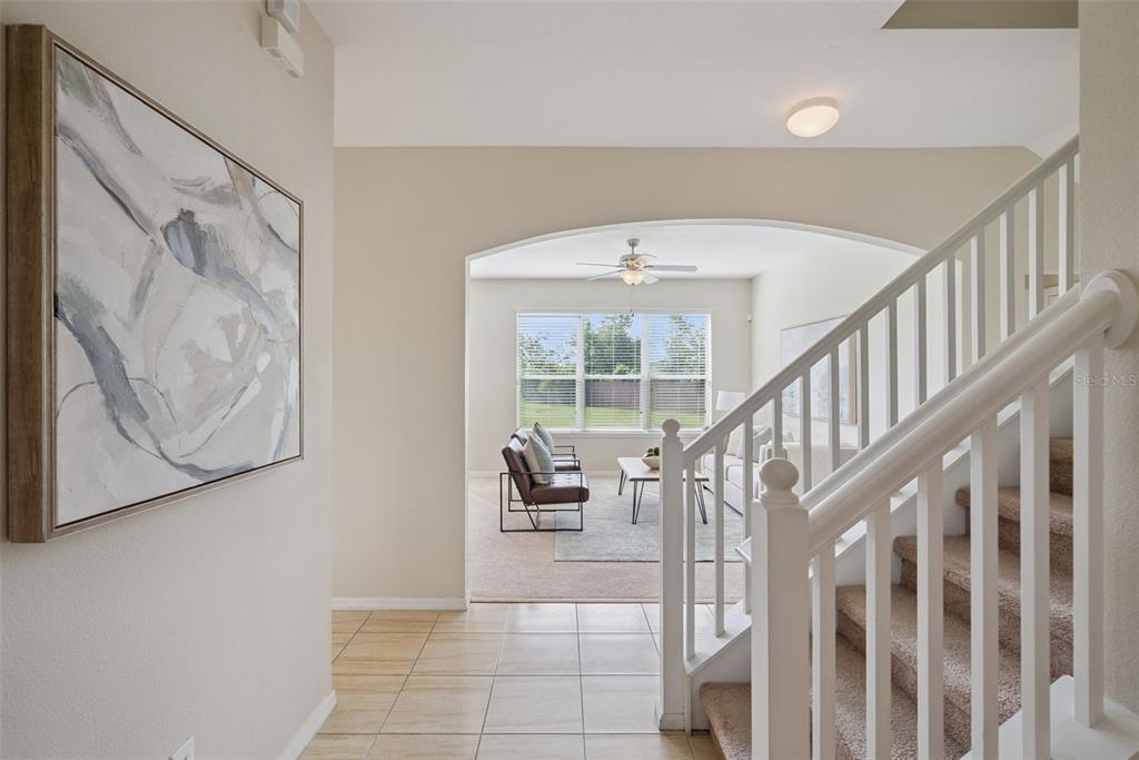A tiled entryway leads to a carpeted living area with a staircase and arched opening — 240 MAGNOLIA PARK TRAIL, SANFORD, FL