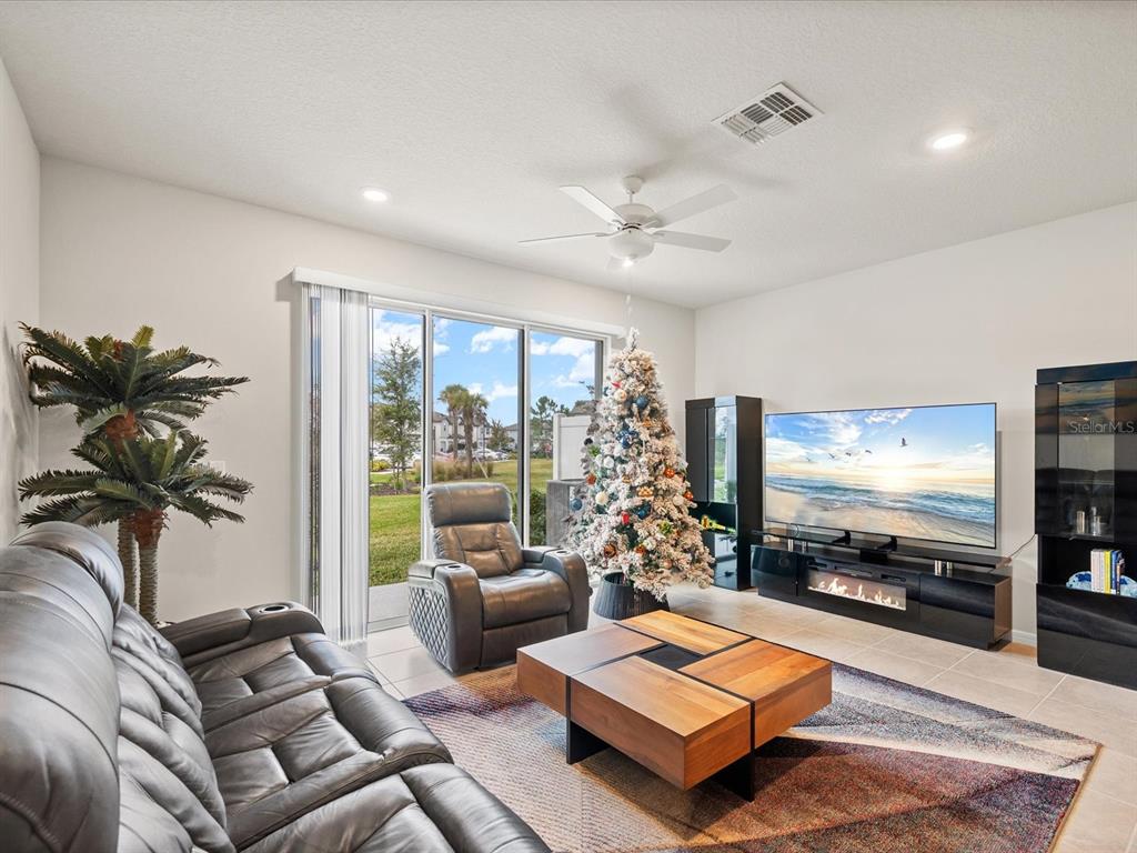A living room features a leather sofa, a recliner, a coffee table, and a Christmas tree — 31428 AMBERVIEW BEND, WESLEY CHAPEL, FL