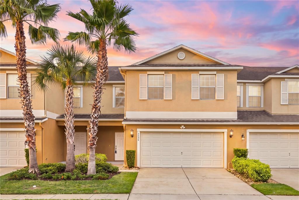 A two-story tan townhouse with a two-car garage and palm trees in the front yard — 3538 RODRICK CIRCLE, ORLANDO, FL