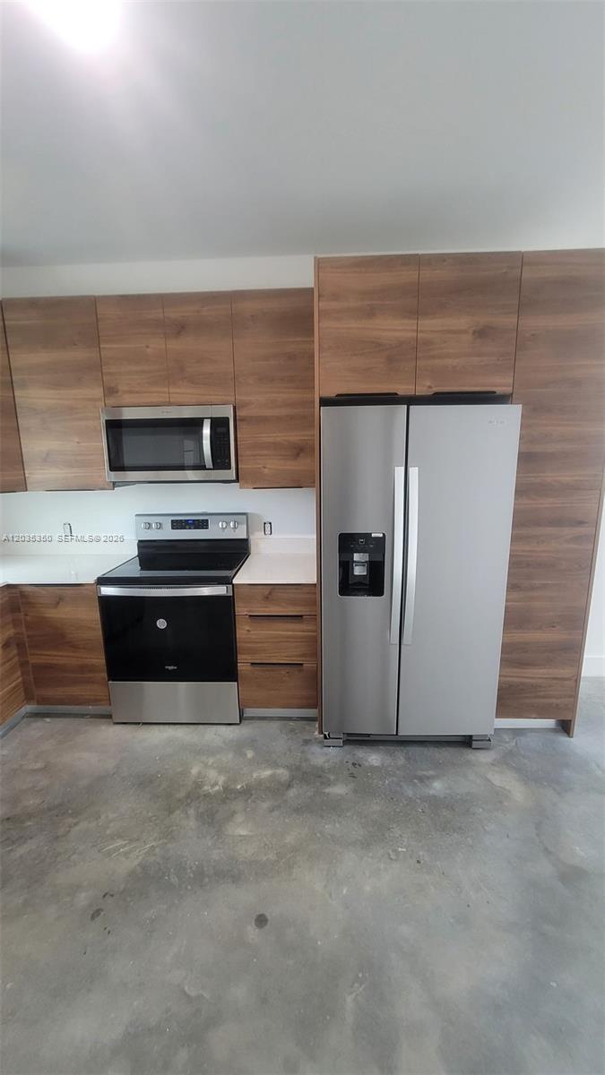 A kitchen features wood-grain cabinets, stainless steel appliances, and a concrete floor — 2146 NW 69th Ter # B, Miami FL 33147, MIAMI, FL