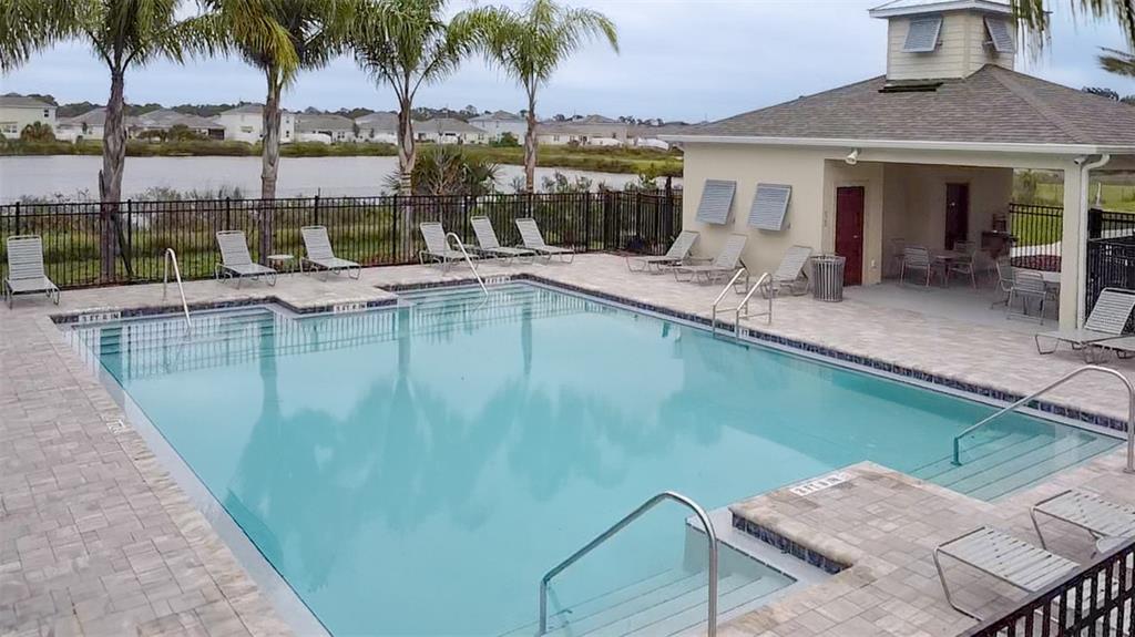A rectangular swimming pool with a surrounding patio, lounge chairs, and a covered clubhouse area — 2706 GOLDEN TROUT LANE, EDGEWATER, FL