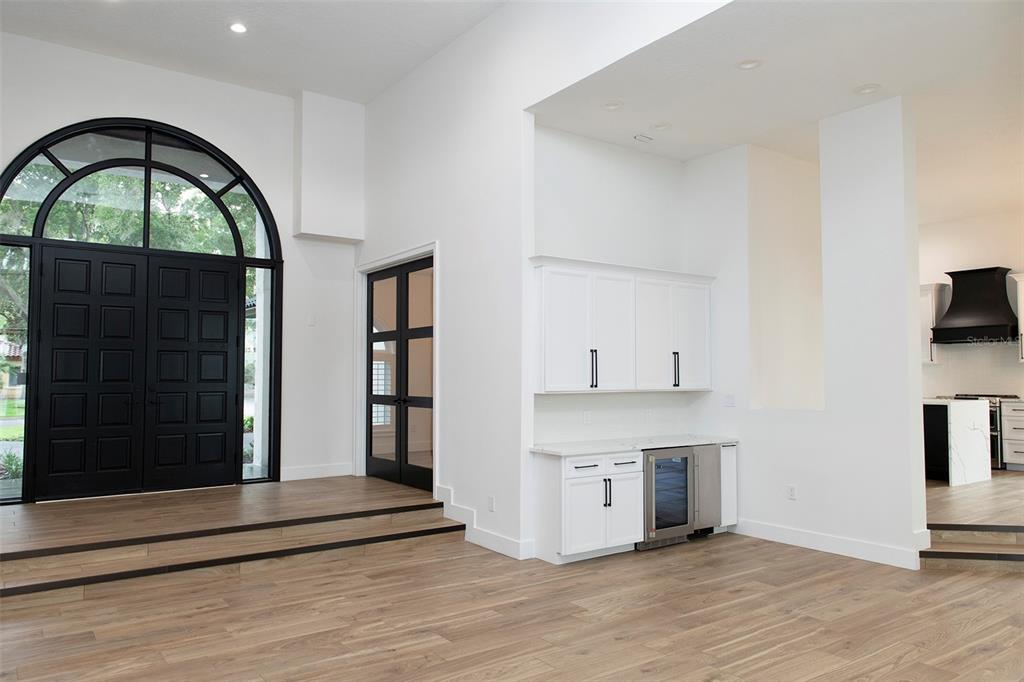 A bright entryway features a black arched double door, wood flooring, and a wet bar — 6119 PAYNE STEWART DRIVE, WINDERMERE, FL