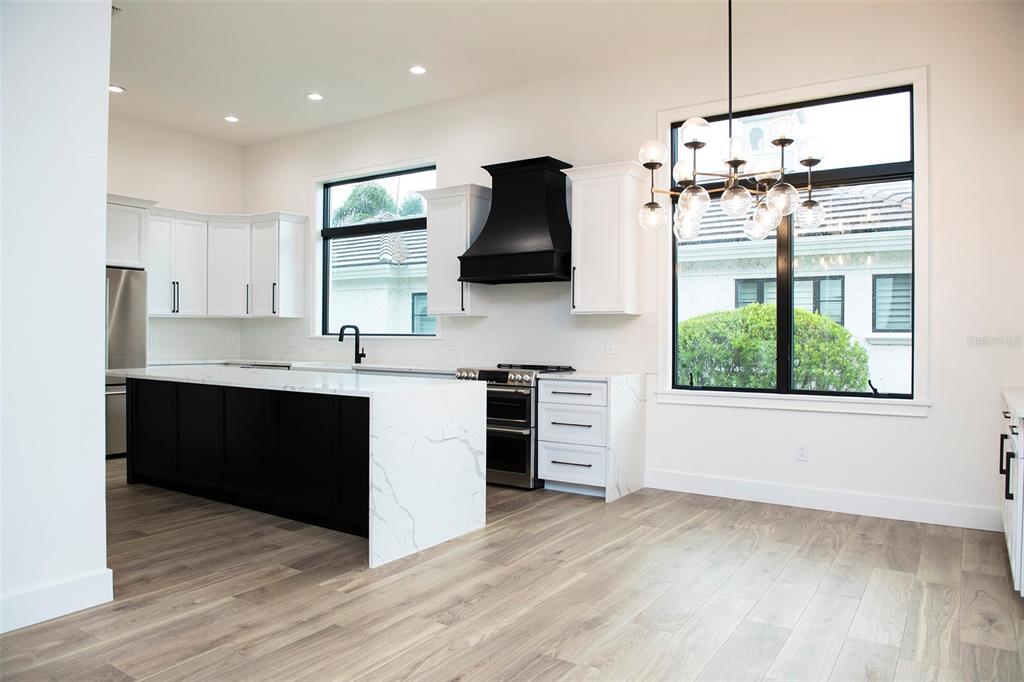 A modern kitchen features white cabinets, a black range hood, and a marble-topped island — 6119 PAYNE STEWART DRIVE, WINDERMERE, FL