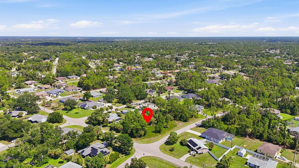 An aerial view shows a vacant, tree-covered lot marked with a red pin in a neighborhood — EASTER TERRACE, NORTH PORT, FL