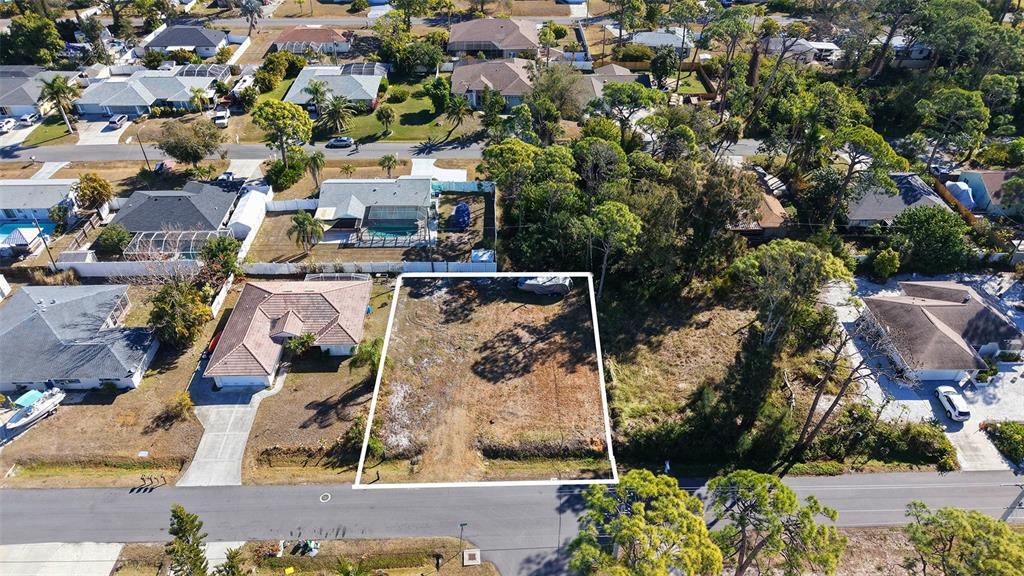 An aerial view shows a vacant, rectangular residential lot outlined in white between two houses — 5993 OSPREY ROAD, VENICE, FL