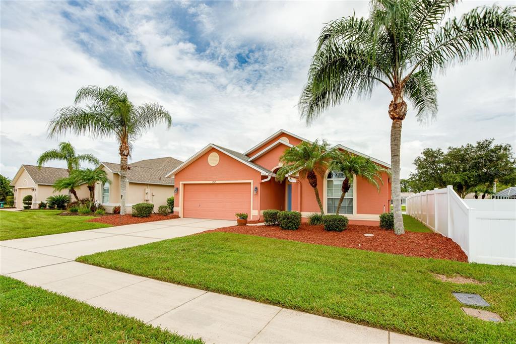 A peach-colored single-story house with a two-car garage, palm trees, and a white vinyl fence — 1767 TRIBUTORY LANE, PORT ORANGE, FL