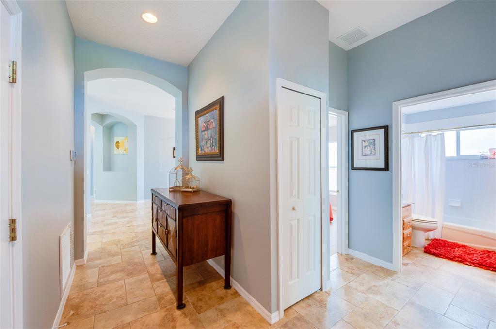 A hallway with light blue walls, tile flooring, a wooden console table, and a bathroom — 1767 TRIBUTORY LANE, PORT ORANGE, FL