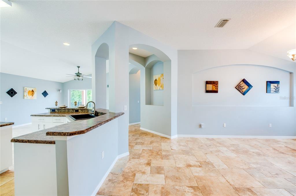A kitchen with a granite breakfast bar opens to a living area with arched wall niches — 1767 TRIBUTORY LANE, PORT ORANGE, FL