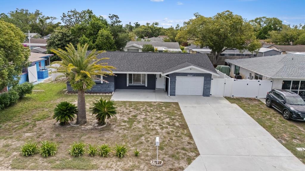 An aerial view of a single-story house with a gray exterior, palm tree, and driveway — 10220 OAK HILL DRIVE, PORT RICHEY, FL
