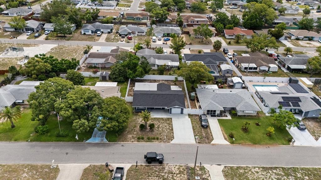 An aerial view shows a suburban street with single-story houses, driveways, and green lawns — 10220 OAK HILL DRIVE, PORT RICHEY, FL