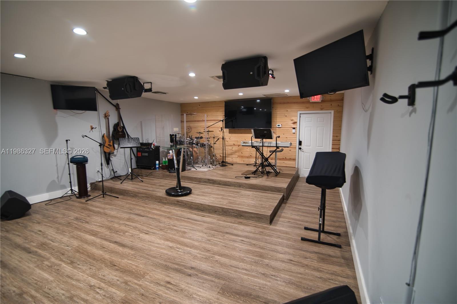 A room features a raised wooden stage with musical instruments, audio equipment, and wood-paneled walls — 15947 NE 19th Pl, North Miami Beach FL 33162, NORTH MIAMI BEACH, FL