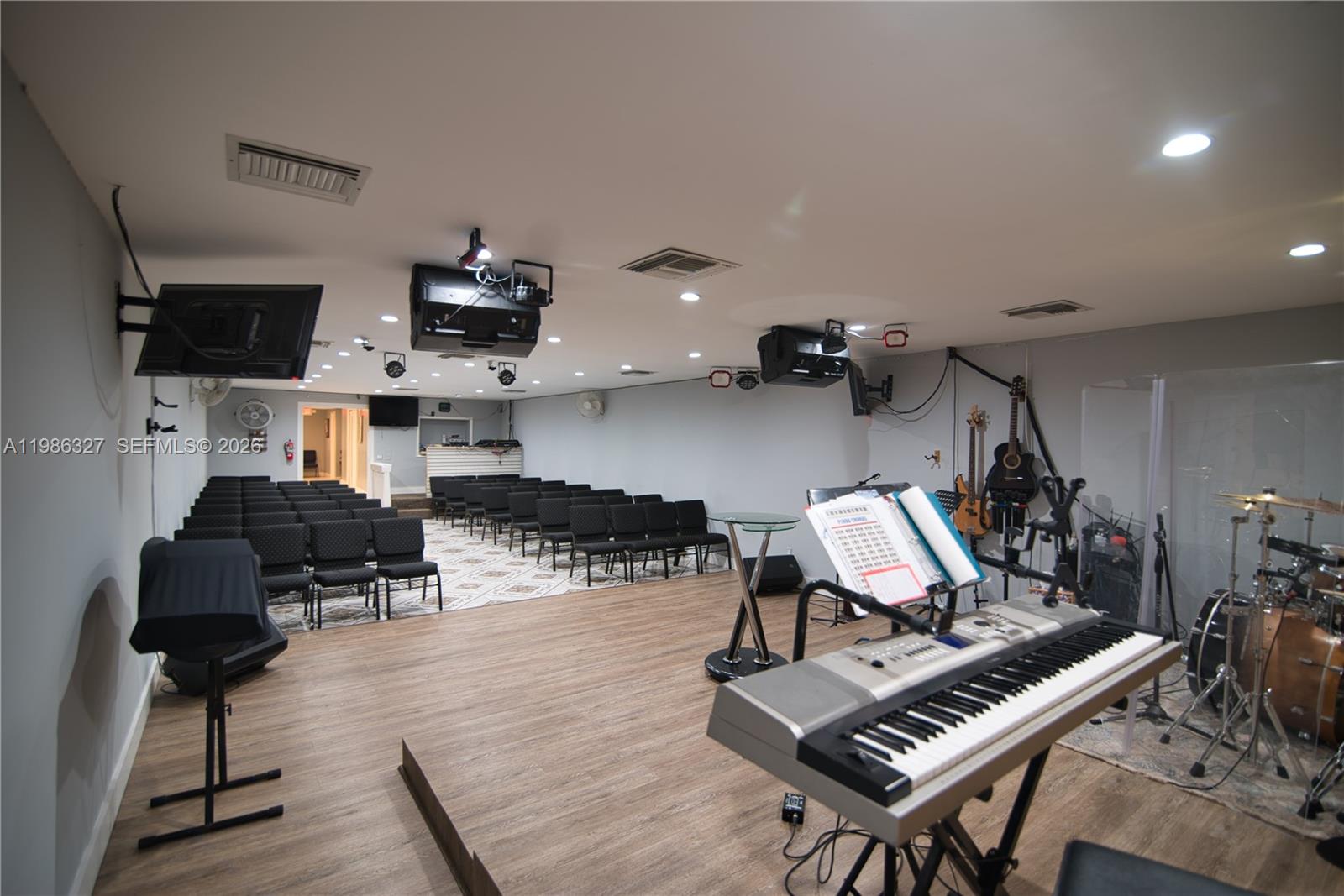 A church sanctuary features rows of chairs, a stage with musical instruments, and recessed lighting — 15947 NE 19th Pl, North Miami Beach FL 33162, NORTH MIAMI BEACH, FL