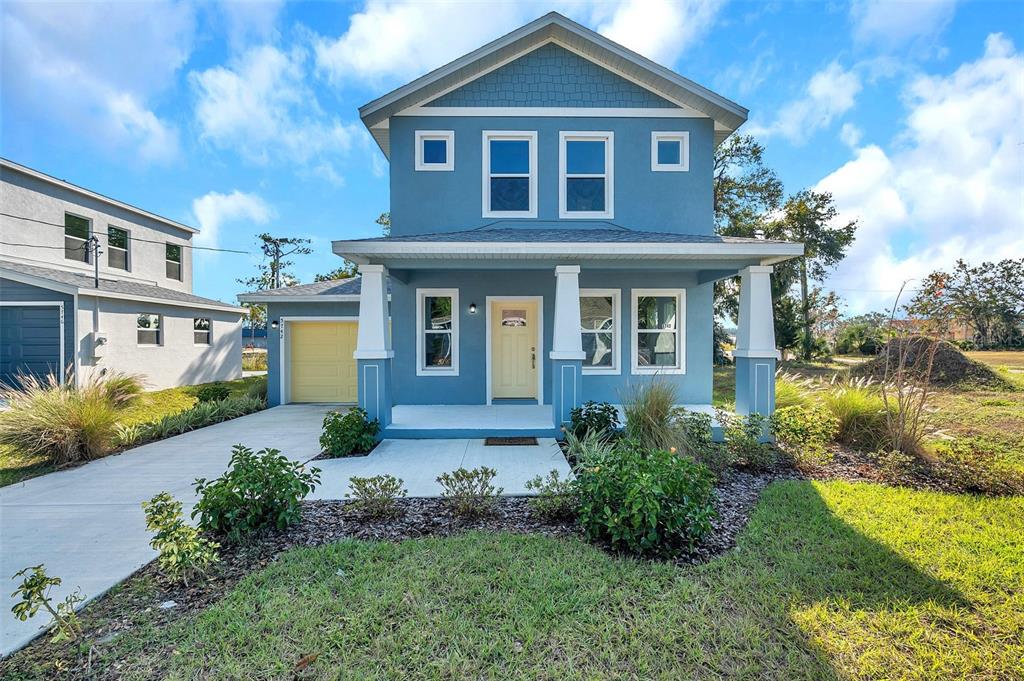 A two-story blue house with a front porch, yellow door, and attached garage — 5742 MEADOWLANE STREET, NEW PORT RICHEY, FL
