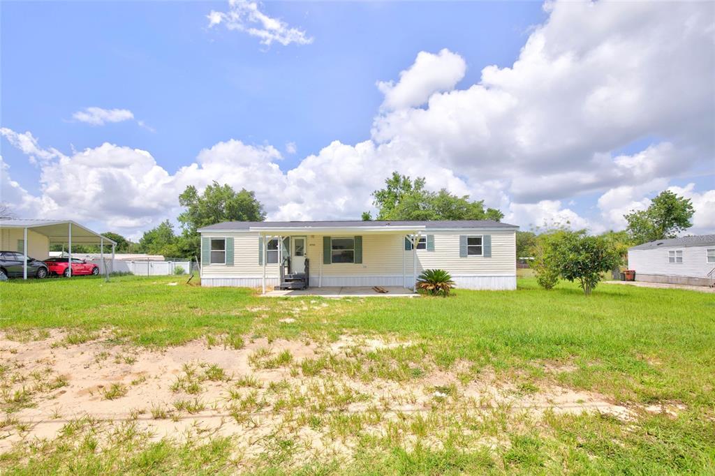 A single-story manufactured home with light siding, a front porch, and a grassy yard — 6766 NE 1ST PLACE, OCALA, FL