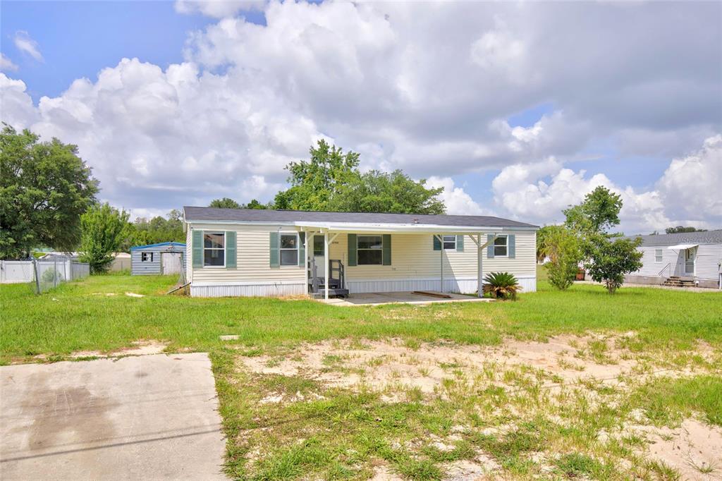 A single-story manufactured home with light siding and a covered front porch sits on grass — 6766 NE 1ST PLACE, OCALA, FL