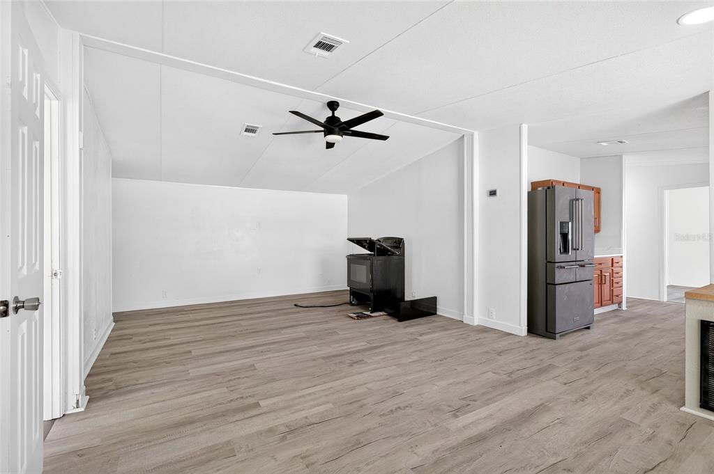 An open-concept living area features light wood-look flooring, white walls, and a black ceiling fan — 6766 NE 1ST PLACE, OCALA, FL