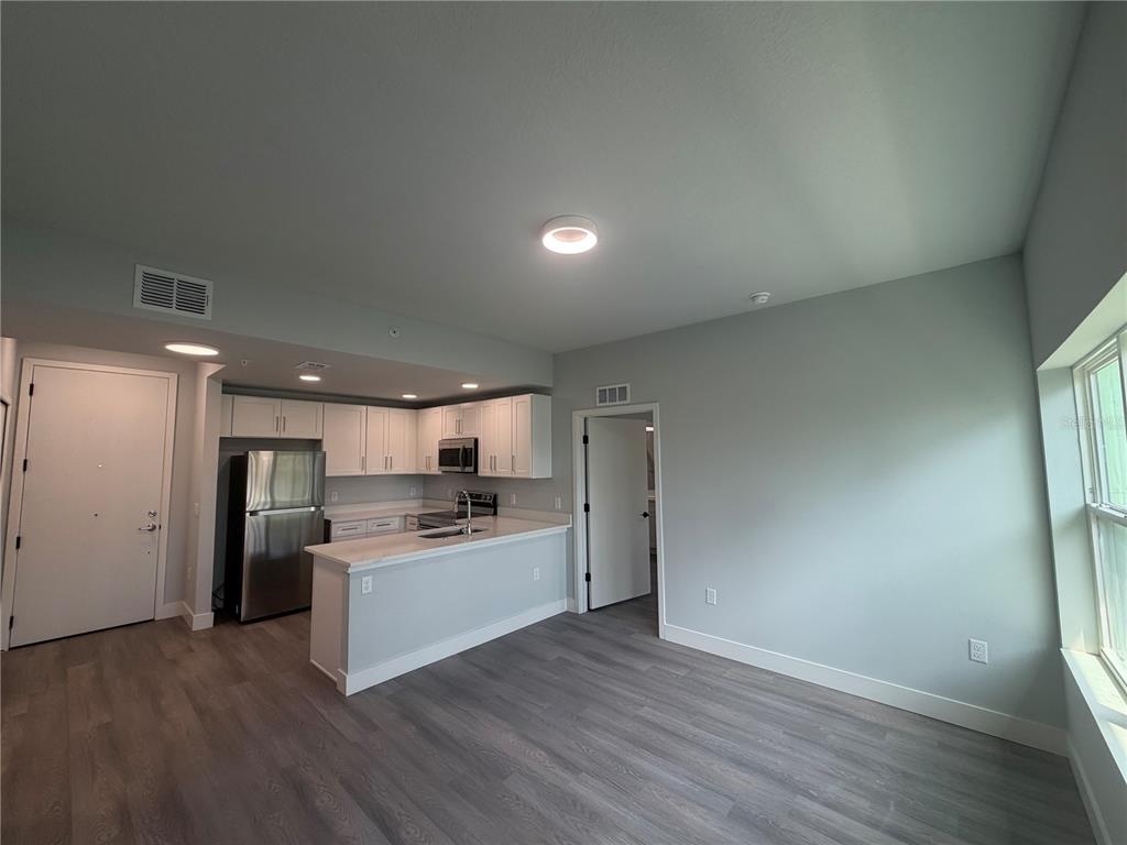 A kitchen with white cabinets and stainless steel appliances opens into a living area — 2240 FLORIDA DRIVE UNIT 103, DELTONA, FL