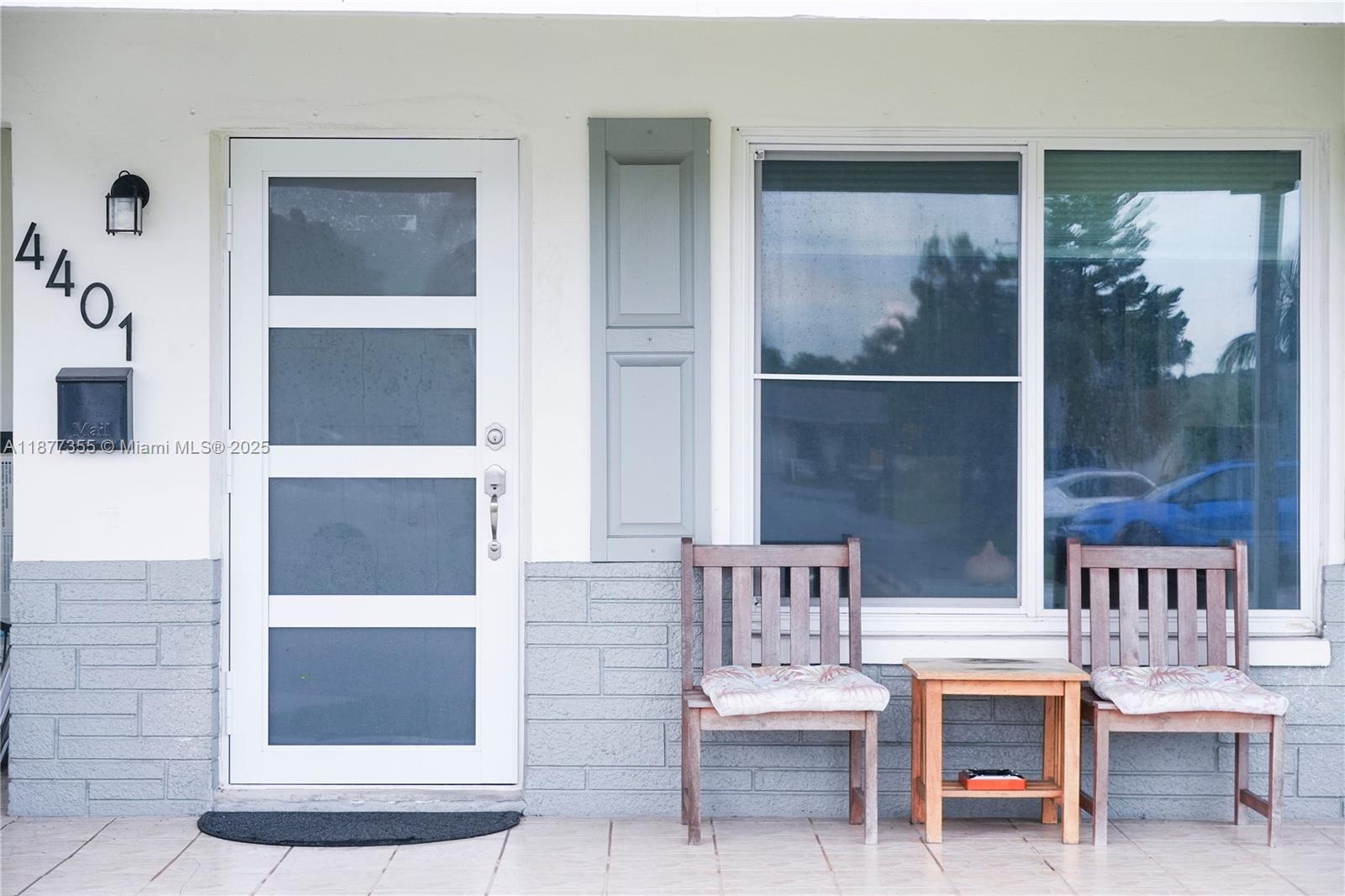 A white front door and a large window are on a porch with two chairs — 4401 NW 45th St, Tamarac FL 33319, TAMARAC, FL