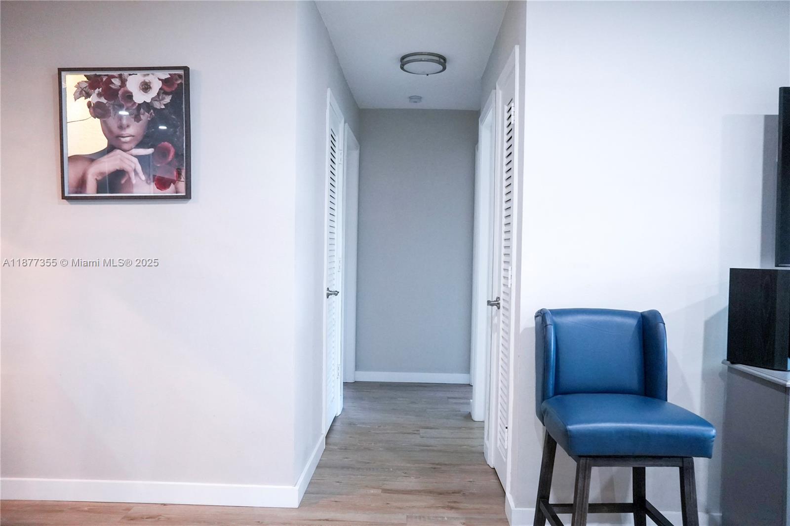 A hallway with light wood flooring connects two white louvered doors under a ceiling light — 4401 NW 45th St, Tamarac FL 33319, TAMARAC, FL