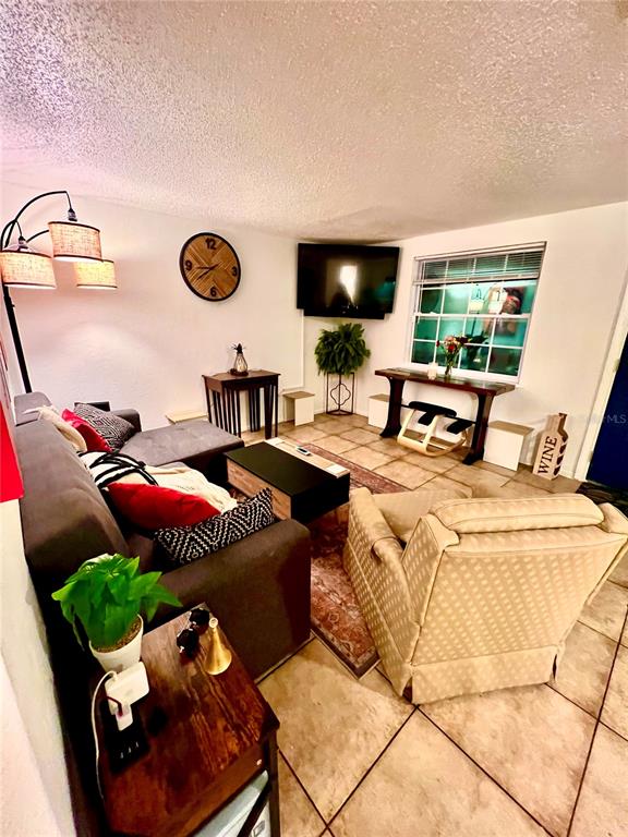 A living room features a sectional sofa, a recliner, a coffee table, and a corner television — 1011 57TH AVENUE TERRACE E, BRADENTON, FL