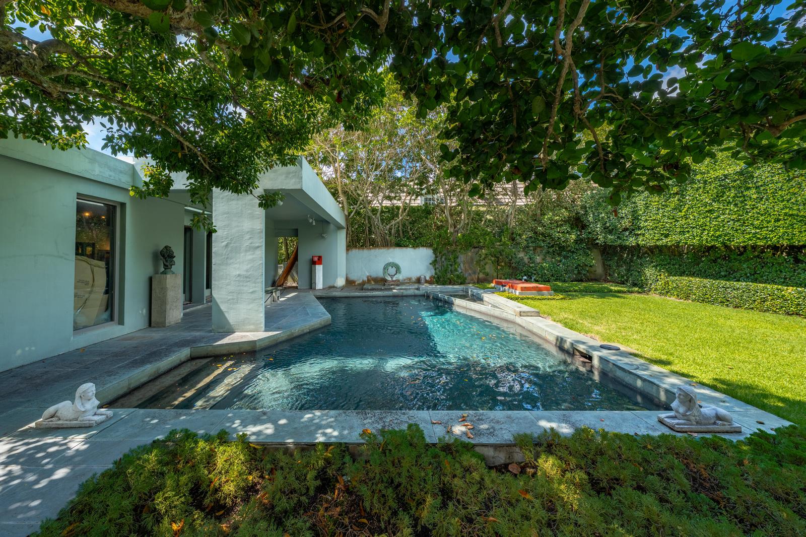 A backyard swimming pool with stone decking, statues, and a covered patio area — 1496 N Lake Way, Palm Beach FL 33480, PALM BEACH, FL