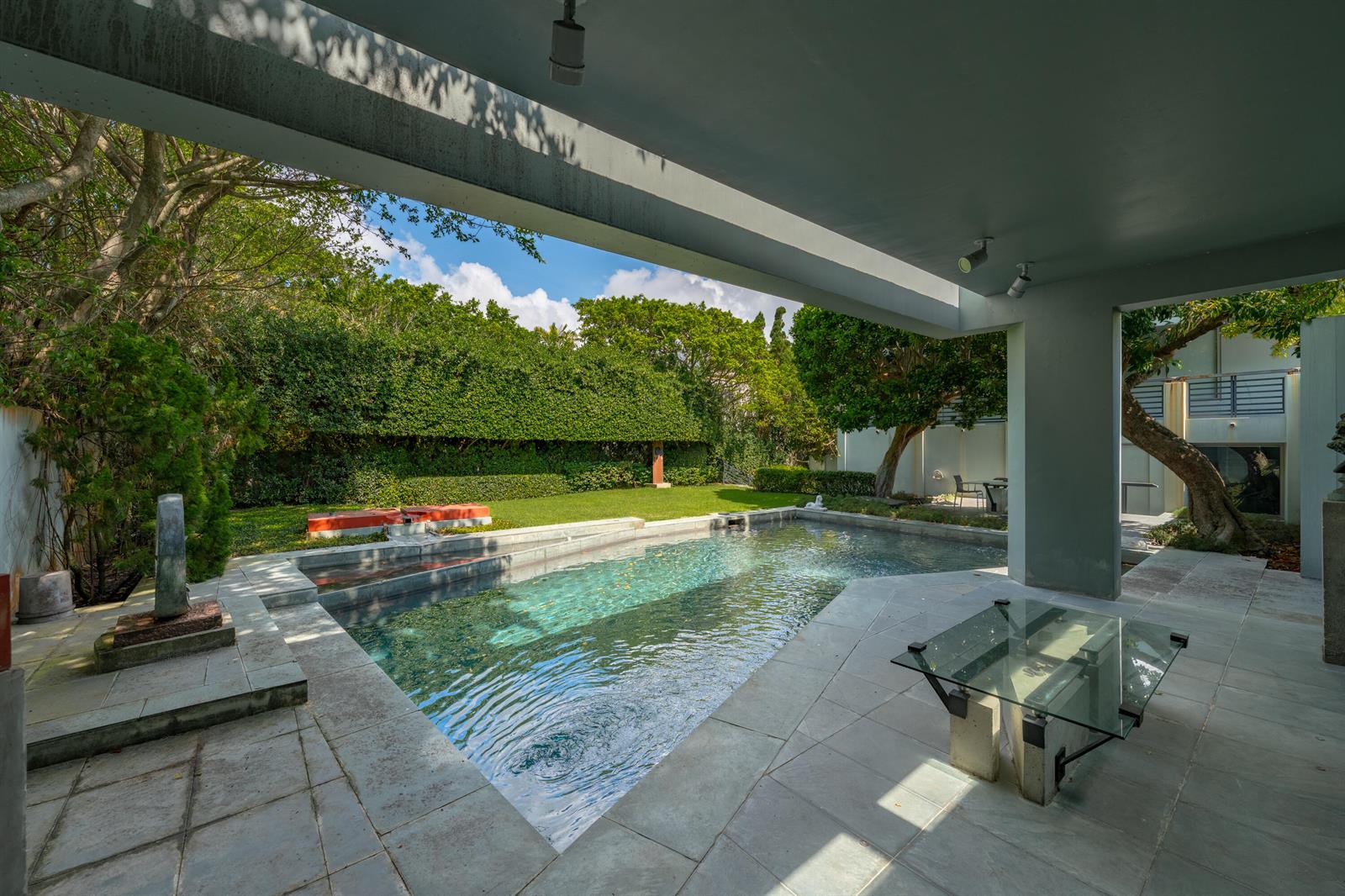 A covered patio with a glass table overlooks a swimming pool and a landscaped backyard — 1496 N Lake Way, Palm Beach FL 33480, PALM BEACH, FL