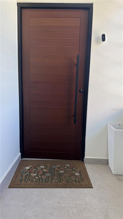 A modern wood-grain front door with a long black handle sits beside a doorbell camera — VILLA CAPARRA TOWER 44 A UNIT 6-A, GUAYNABO, PR