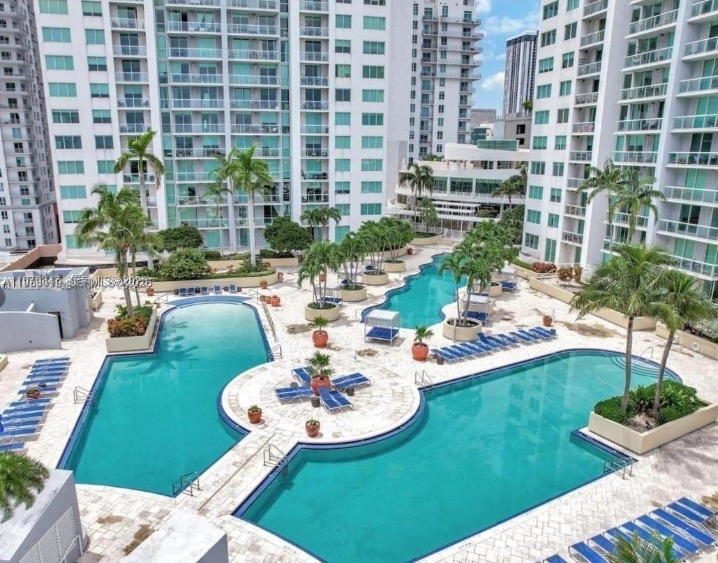 An elevated view of a multi-section swimming pool surrounded by palm trees and apartment buildings — 244 NE Biscayne Blvd # 440, Miami FL 33132, MIAMI, FL