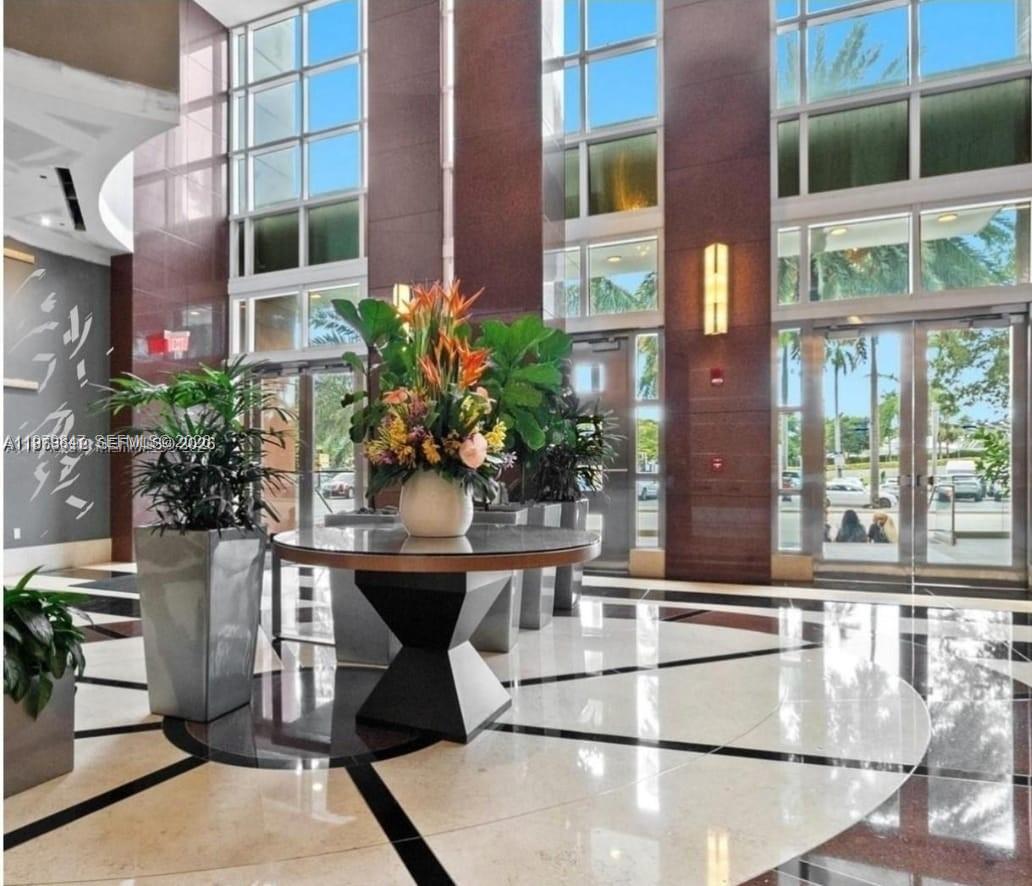 A bright lobby features a central floral arrangement on a round table and marble flooring — 244 NE Biscayne Blvd # 440, Miami FL 33132, MIAMI, FL