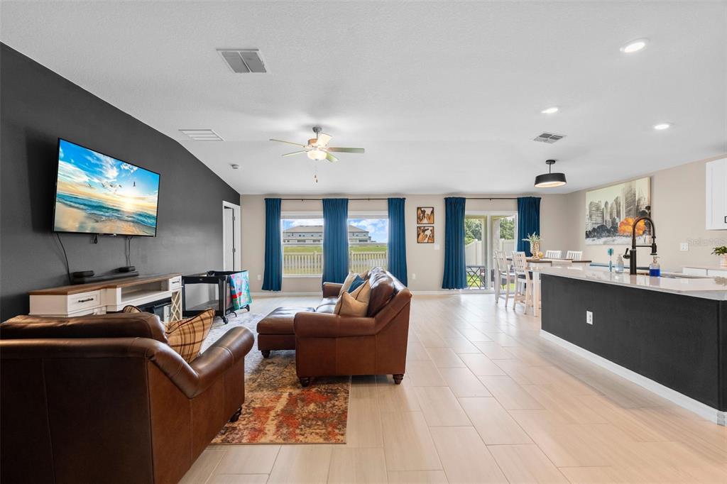 An open-concept living room and kitchen with dark accent walls, leather furniture, and tile flooring — 13608 SUNSET SAPPHIRE COURT, PARRISH, FL