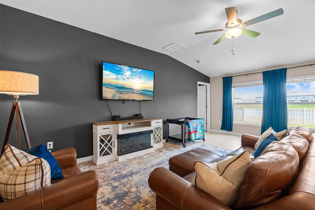 A living room features a dark accent wall, a television, and brown leather furniture — 13608 SUNSET SAPPHIRE COURT, PARRISH, FL